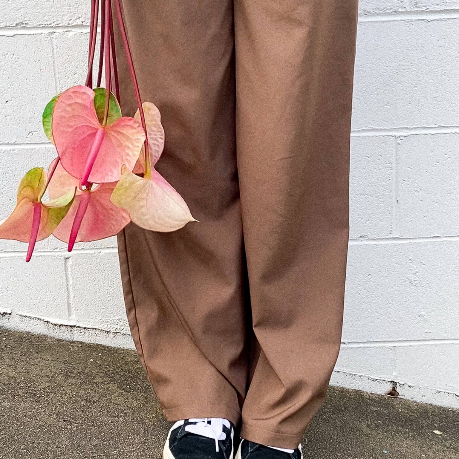 A lady in brown pants holding Anthuriums - Poppy Rose Flower Delivery in Brisbane