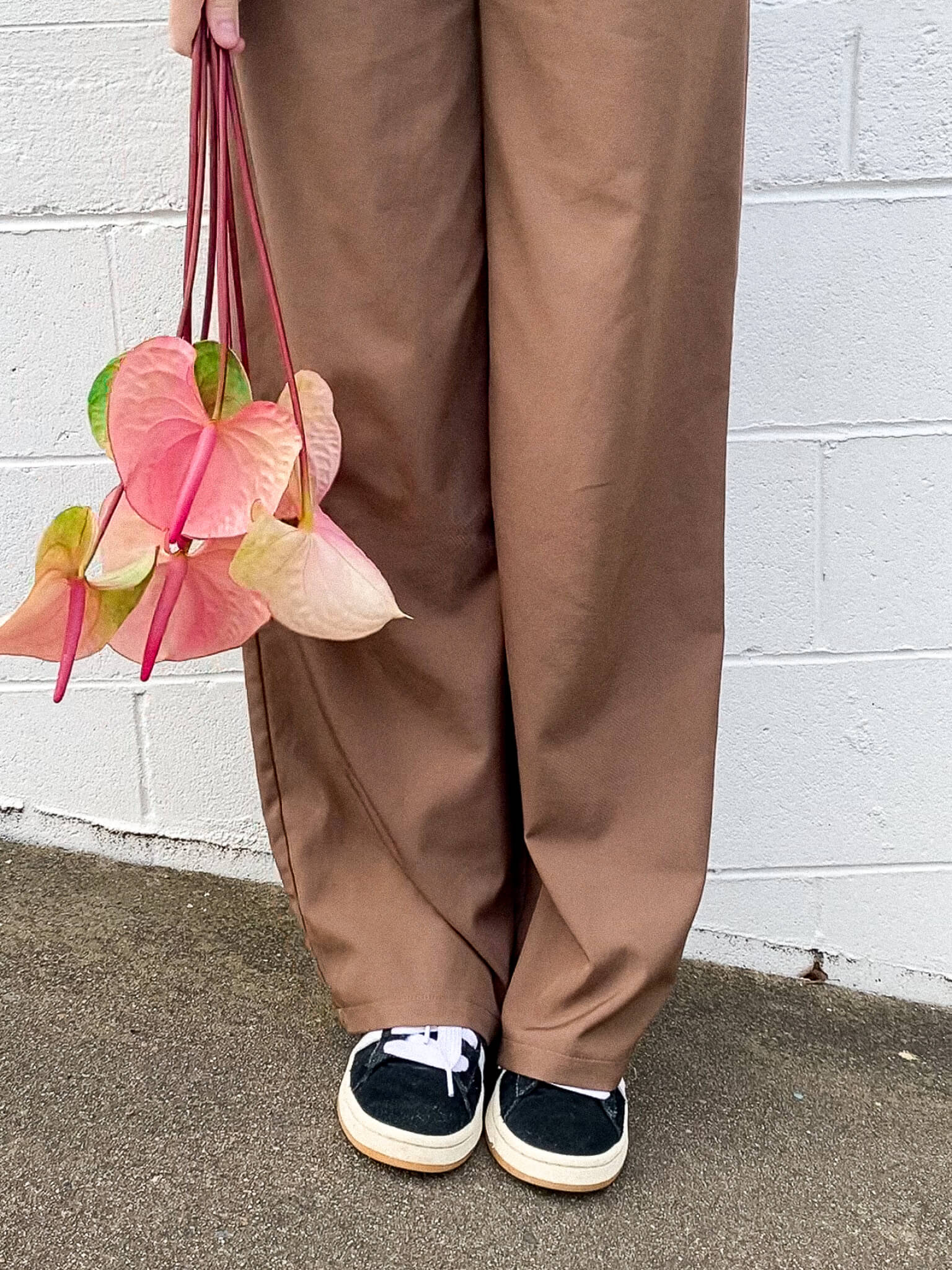 A lady in brown pants holding Anthuriums - Poppy Rose Flower Delivery in Brisbane