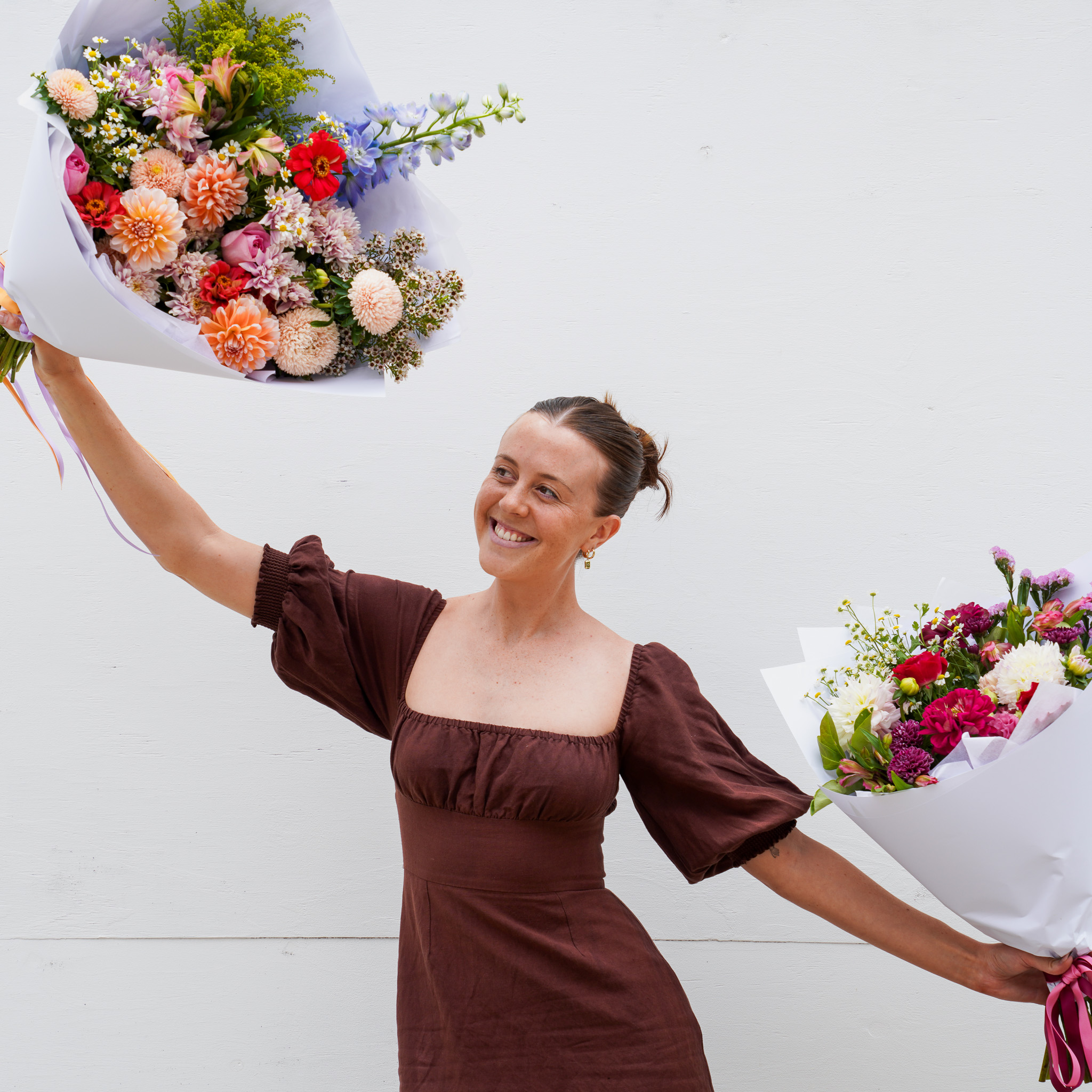 A happy woman dancing with bunches of flowers in Brisbane