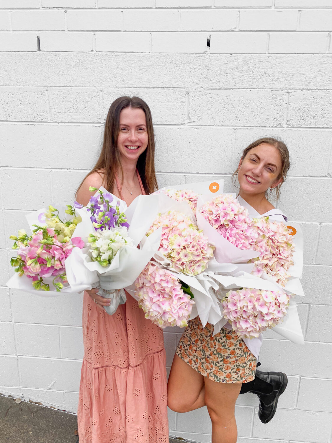 Two women holding flowers and laughing at Poppy Rose Brisbane